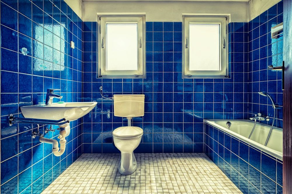 Altes Bad mit blauen Fliesen, Badewanne und WC