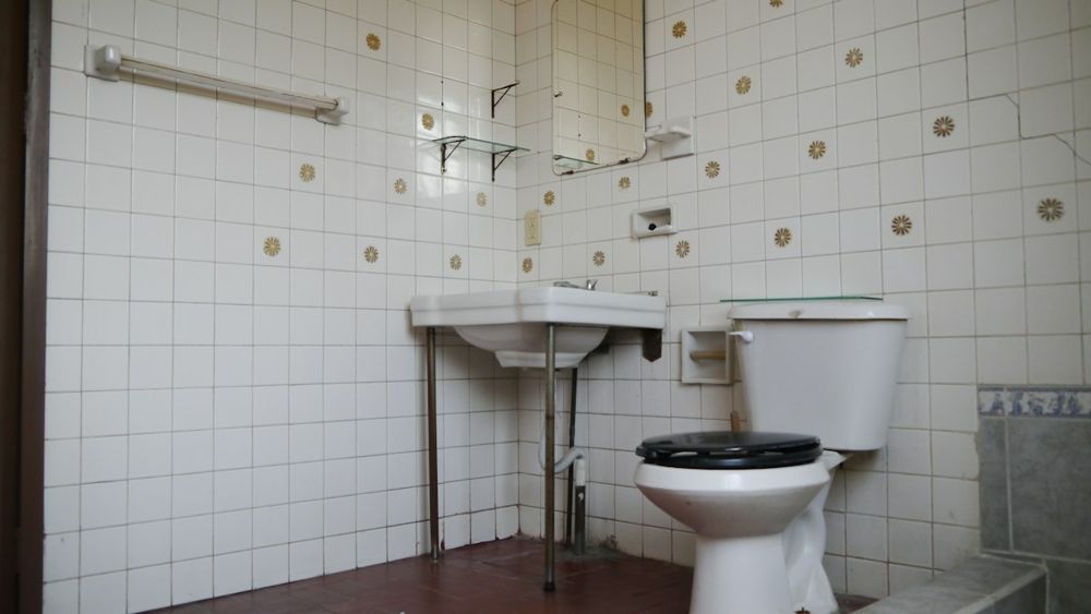 Altes Bad mit weißen Fliesen, Stand-WC und Waschbecken